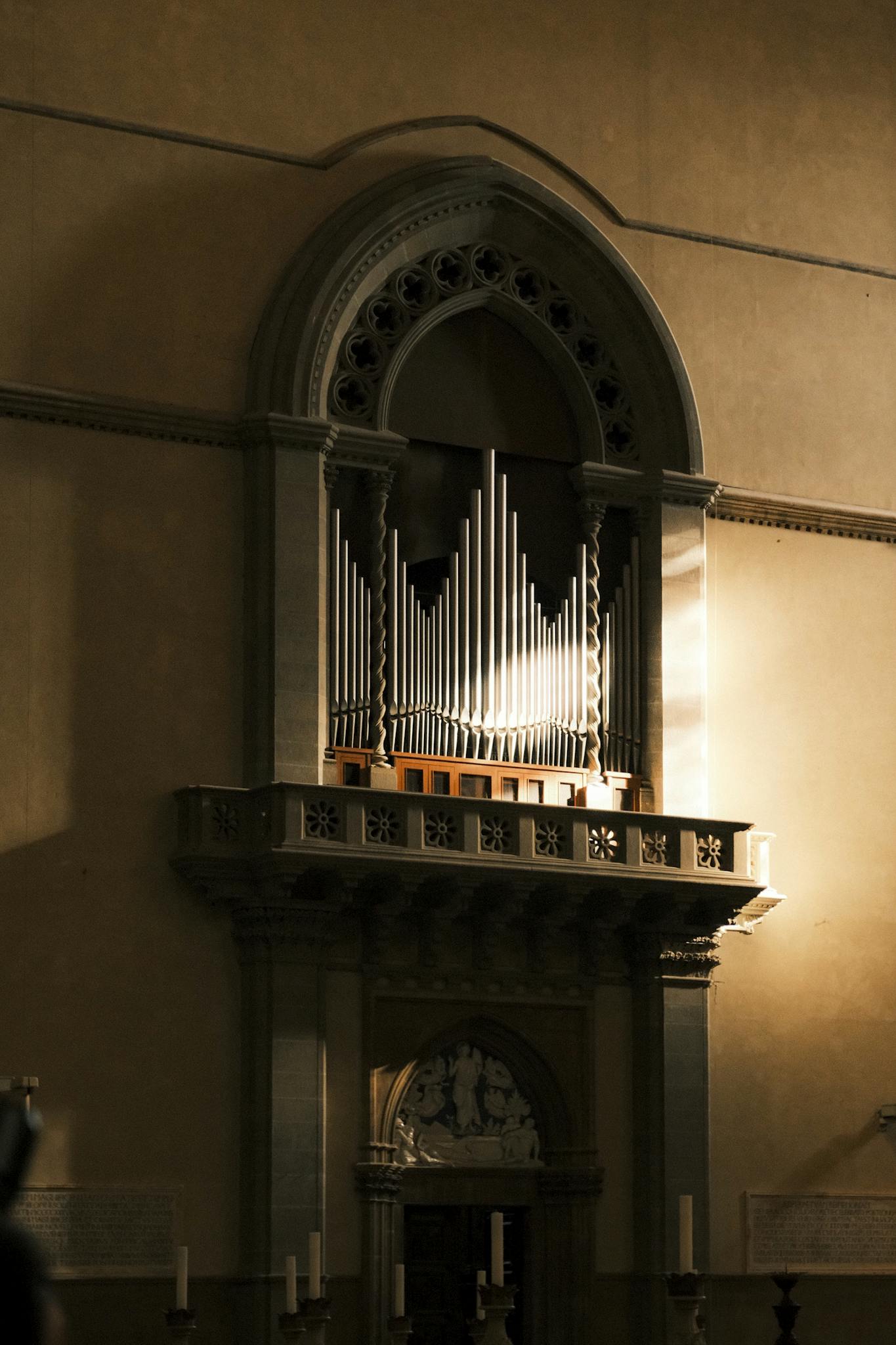 A beautifully lit pipe organ in a historic church setting, showcasing gothic architecture.
