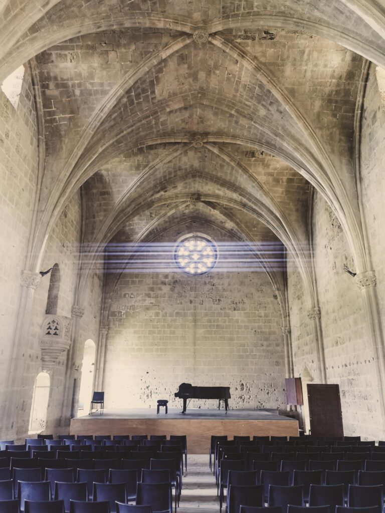 Elegant Gothic cathedral interior featuring a grand piano on stage beneath a stunning rose window.