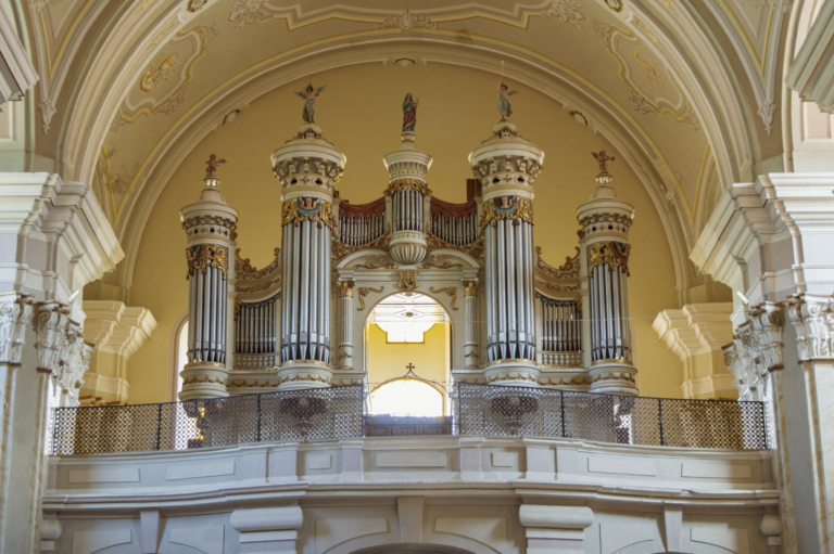 Intricately designed church organ within a beautifully ornate cathedral interior.